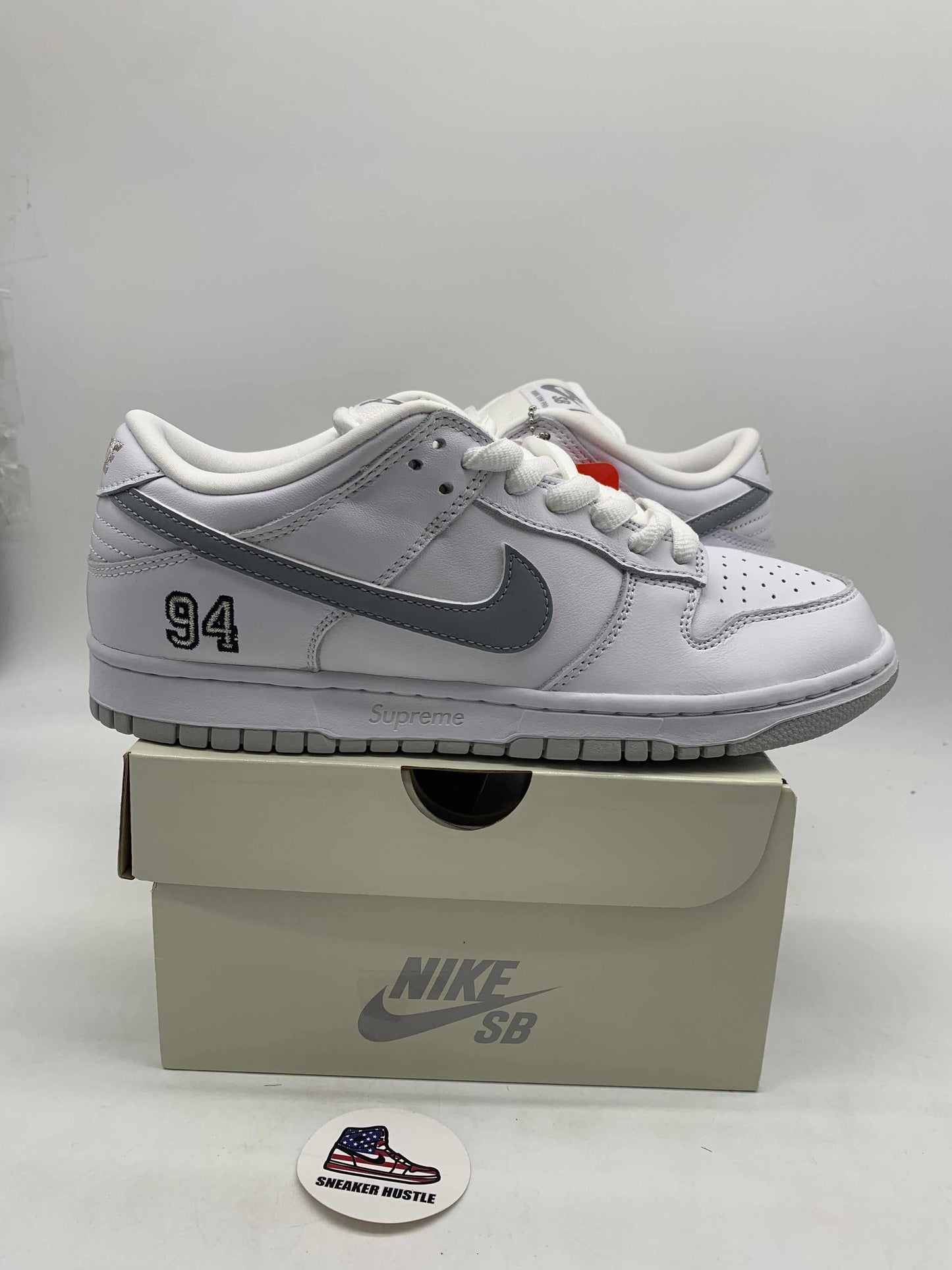 White and metallic silver Nike SB Dunk Low Supreme 94 sneakers on a Nike SB box