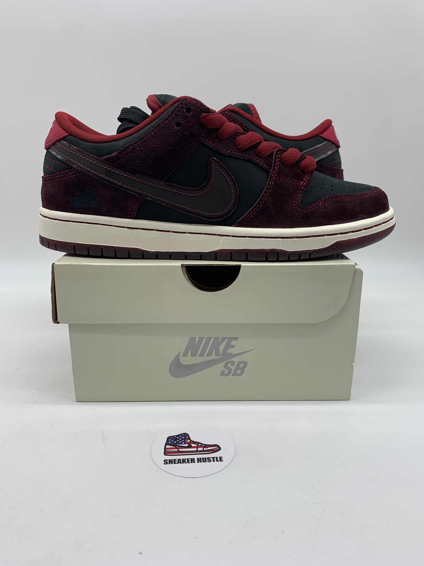 Nike SB Dunk Low Riot Skateshop sneakers in black and burgundy on a Nike SB shoebox