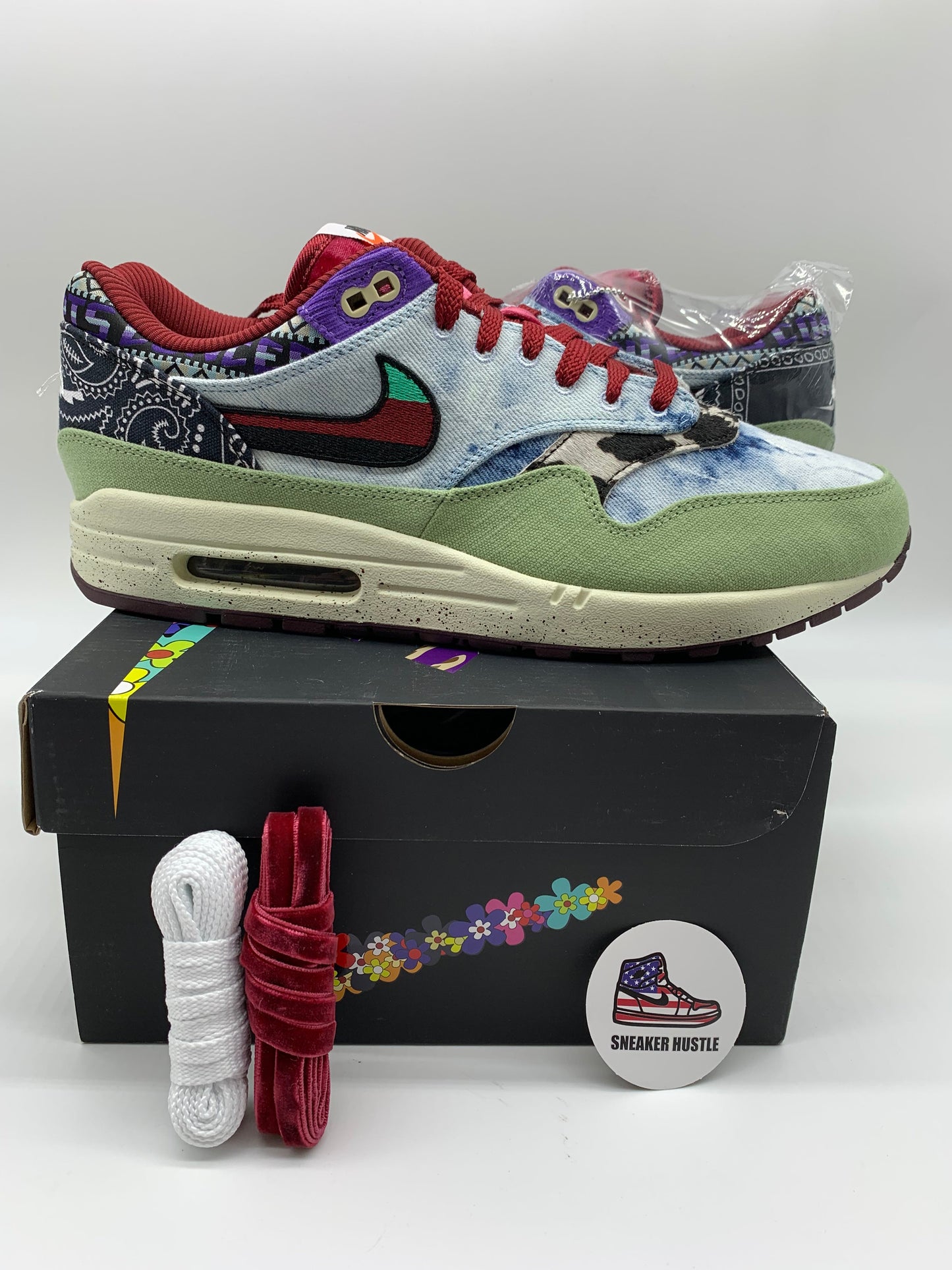 Nike Air Max 1 SP Concepts Mellow sneaker in multicolor with green suede, red laces, and paisley pattern design on black box with extra laces and pin badge