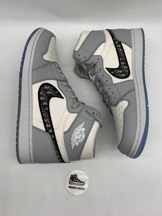 Pair of Air Jordan 2025 sneakers in gray and white with black custom swoosh, displayed on light background for Air Jordan 2025 Los Angeles release.