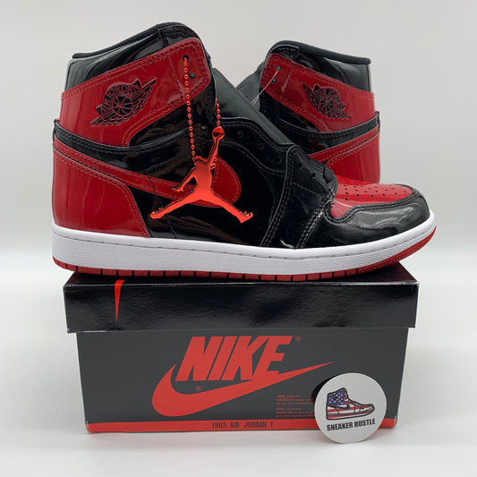 Pair of Jordan 1 Retro High OG Patent Bred sneakers in black and red on Nike box