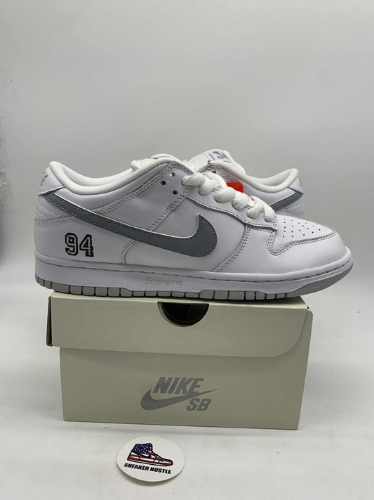 White and metallic silver Nike SB Dunk Low Supreme 94 sneakers on a Nike SB box